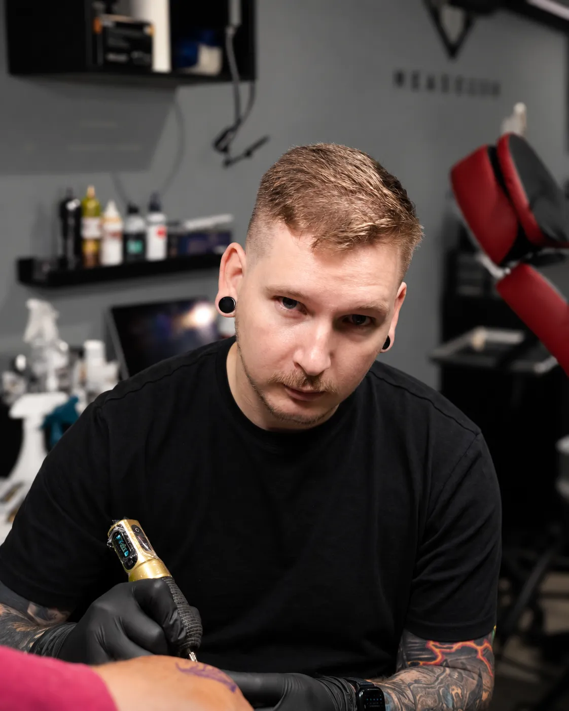 Ross tattooing a client, holding the machine